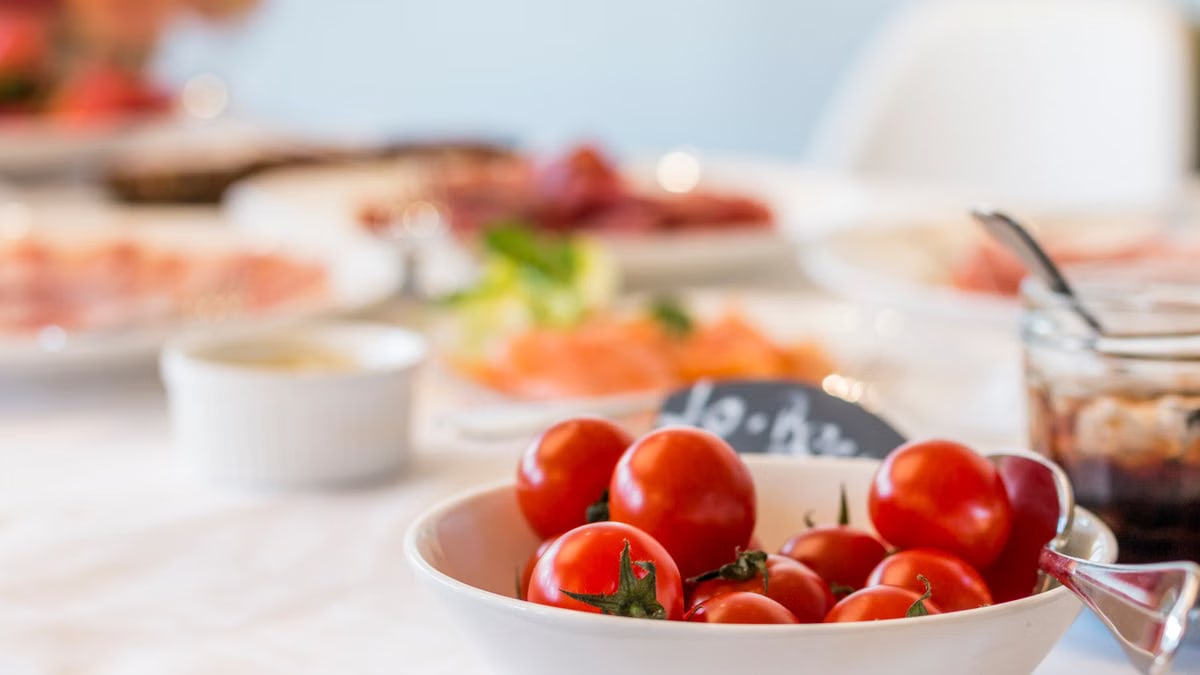 Close-up shot of vibrant cherry tomatoes in a bowl on a well-set dining table.