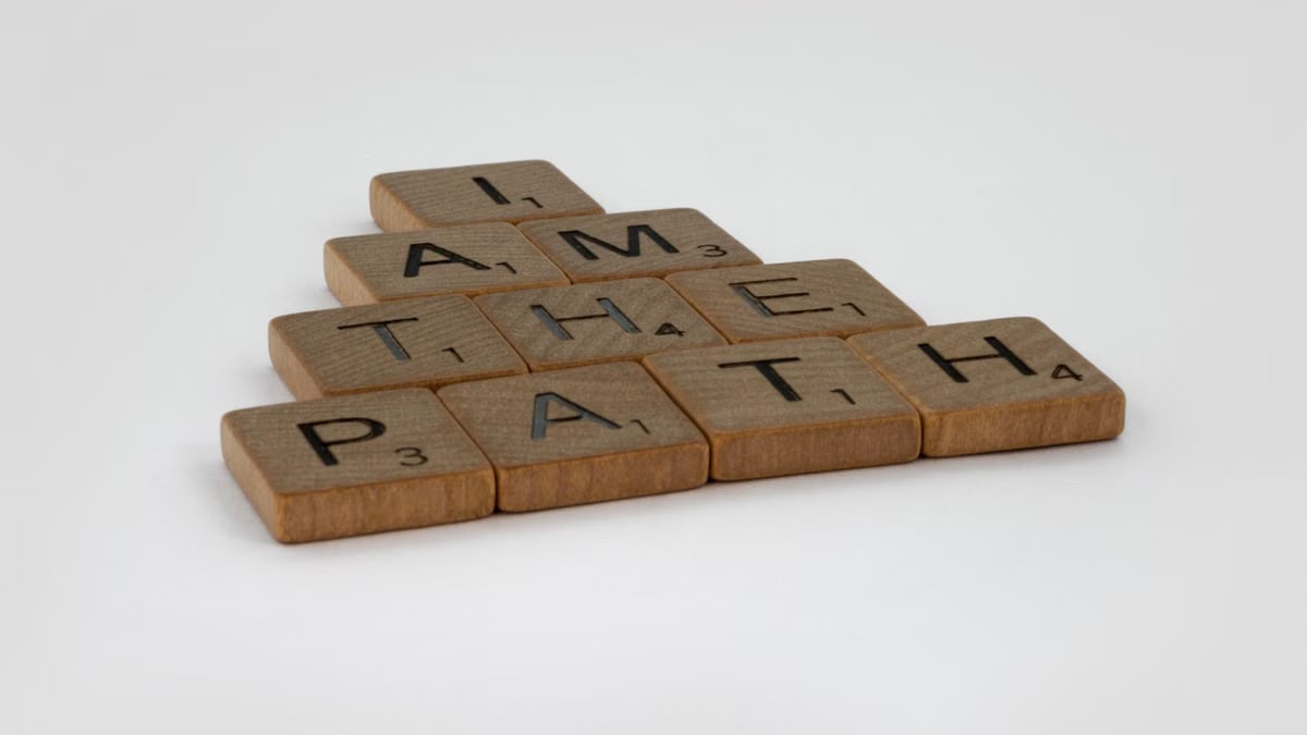 Scrabble tiles spelling out 'I Am The Path' on a white surface, inspiring message.